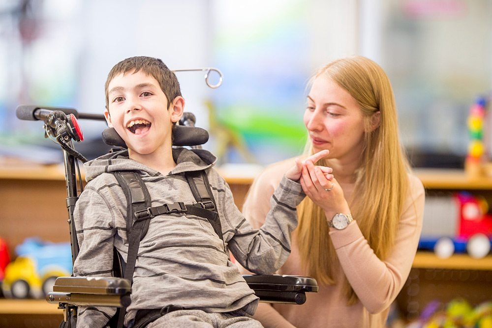 Child with cerebral palsy interacting with therapist, showing communication and speech development difficulties